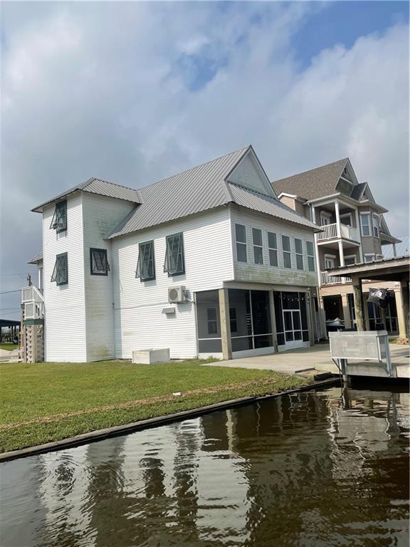 back of property featuring a yard, a water view, and metal roof