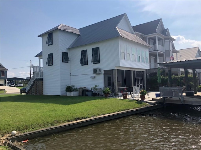 back of house featuring a lawn, a water view, and metal roof