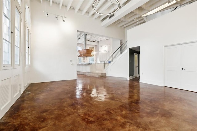 515 Ursulines Ave, New Orleans, LA 70116 - unfurnished living room featuring finished concrete floors, a towering ceiling, and beamed ceiling
