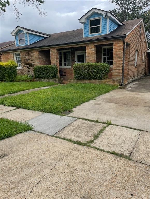 view of front of home featuring brick siding, a front lawn, and concrete driveway