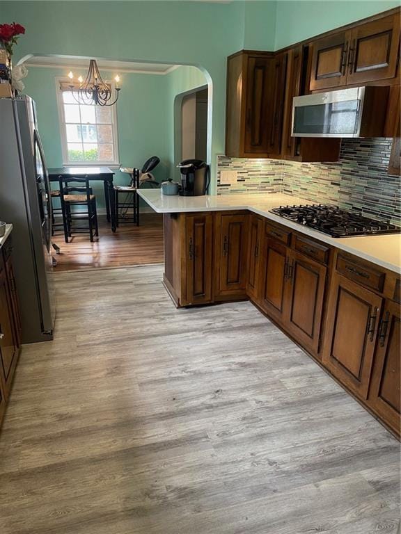 kitchen with light wood-style flooring, arched walkways, light countertops, and stainless steel appliances