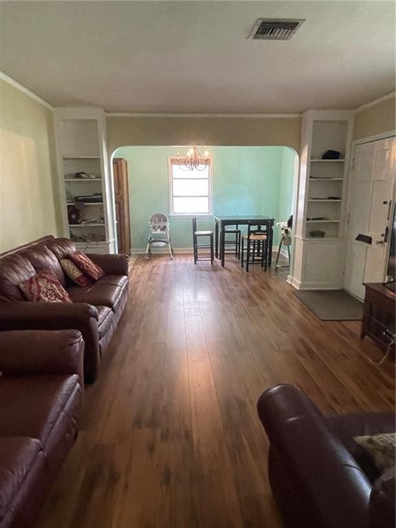 living room featuring crown molding, an inviting chandelier, arched walkways, visible vents, and wood finished floors