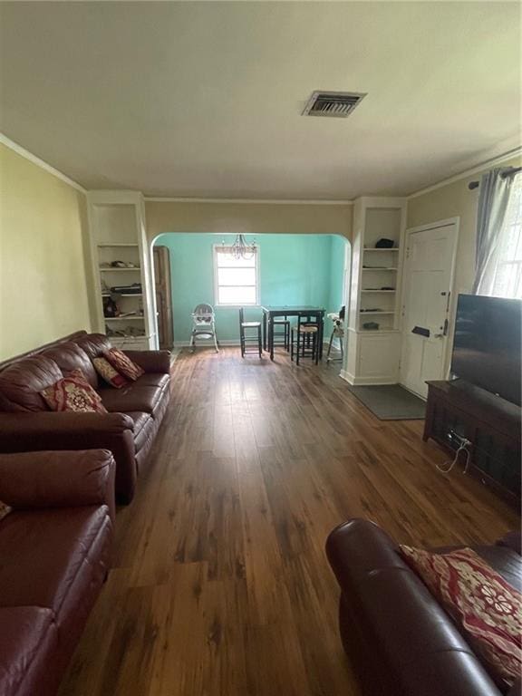 living area featuring visible vents, built in features, arched walkways, ornamental molding, and wood finished floors