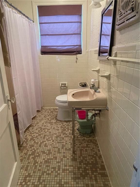 bathroom with a sink, tile walls, toilet, and a shower with shower curtain