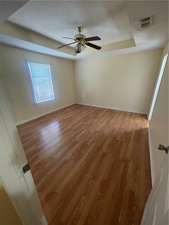 4941 Viola St, New Orleans, LA 70126 - spare room featuring a raised ceiling, wood finished floors, a textured ceiling, and a ceiling fan