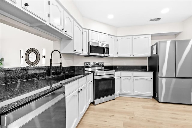 146 Bluefield Dr, Slidell, LA 70458 - kitchen with stainless steel appliances, a sink, white cabinetry, dark stone countertops, and recessed lighting