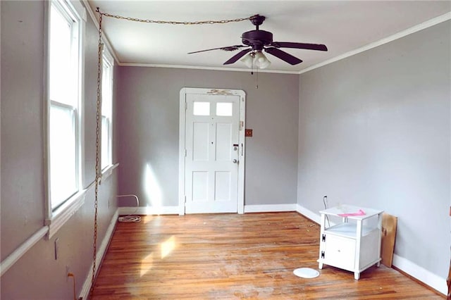 foyer entrance featuring a ceiling fan, ornamental molding, baseboards, and light wood-type flooring