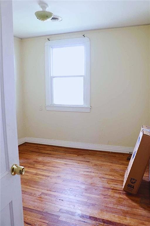 spare room featuring baseboards and wood finished floors