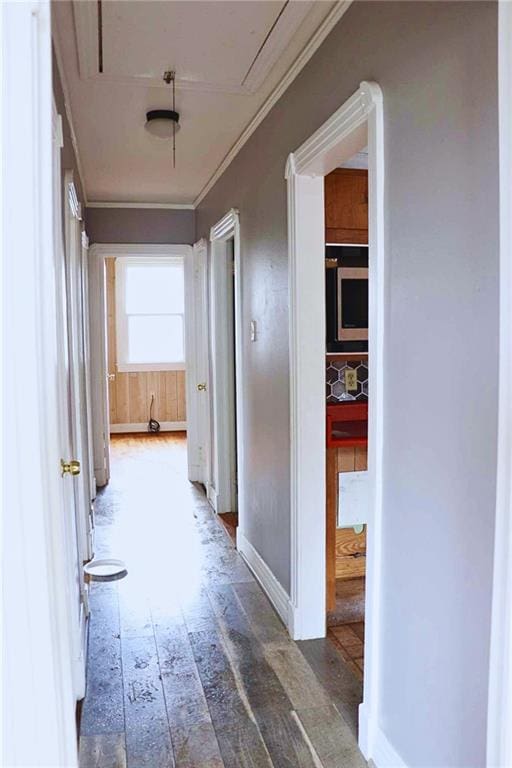 hallway with wood-type flooring, attic access, crown molding, and baseboards