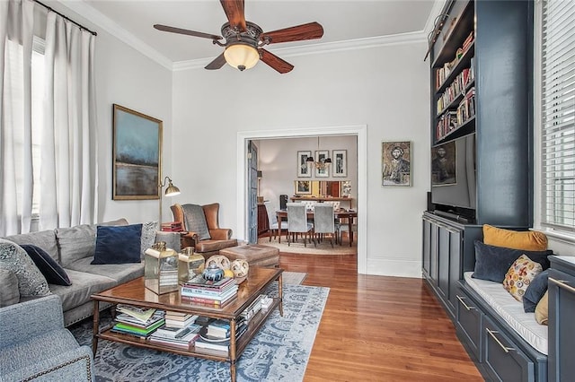 living room featuring baseboards, a ceiling fan, wood finished floors, and crown molding