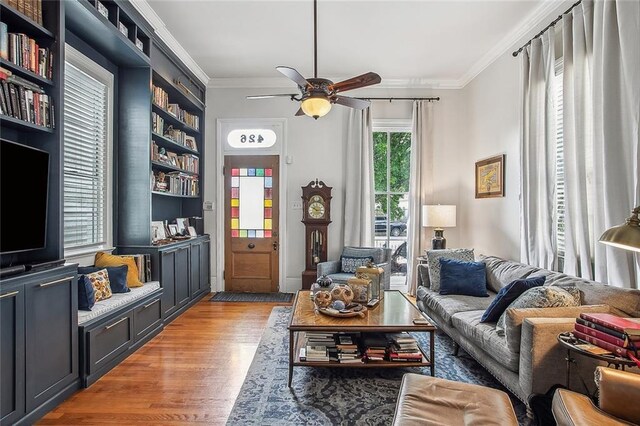 living area with ornamental molding, light wood-style flooring, and a ceiling fan