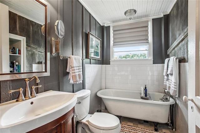 full bathroom with a freestanding tub, toilet, vanity, and tile walls