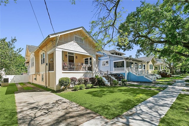 bungalow-style house with covered porch, fence, a front lawn, stairs, and a residential view