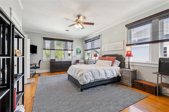 bedroom featuring crown molding, wood finished floors, baseboards, and a ceiling fan