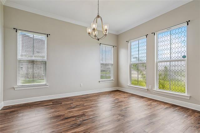 9554 W Keri Ln, Waggaman, LA 70094 - spare room featuring ornamental molding, baseboards, plenty of natural light, a chandelier, and dark wood finished floors