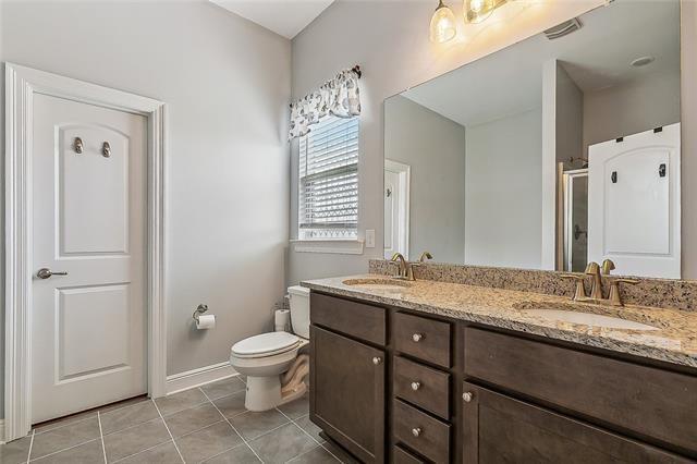 9554 W Keri Ln, Waggaman, LA 70094 - full bathroom featuring double vanity, tile patterned flooring, a stall shower, toilet, and baseboards