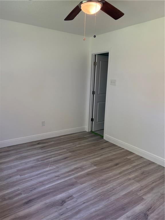 unfurnished room featuring baseboards, a ceiling fan, and wood finished floors