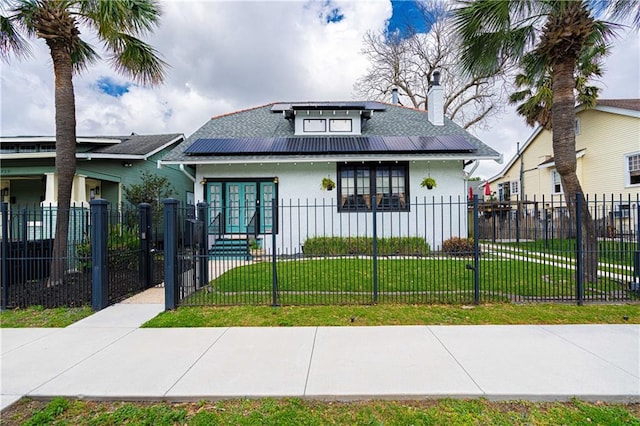 bungalow featuring a fenced front yard, solar panels, a chimney, stucco siding, and a front lawn
