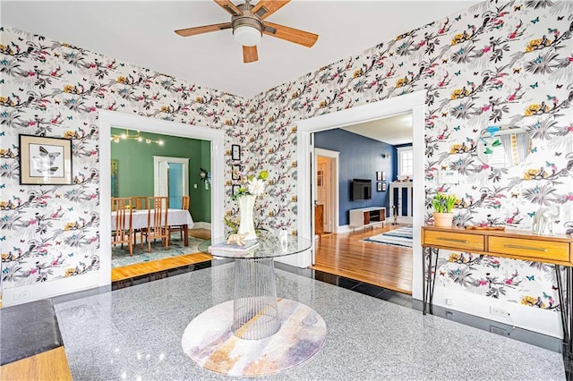 interior space with ceiling fan, baseboards, and wallpapered walls