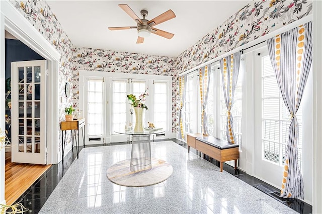 interior space with granite finish floor, wallpapered walls, and a ceiling fan