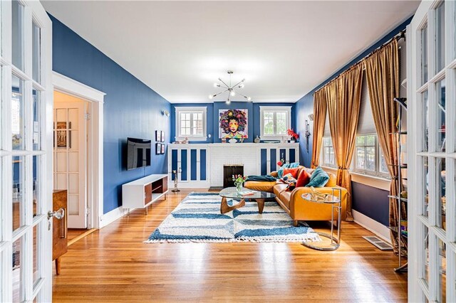 living area with visible vents, french doors, a chandelier, and wood finished floors