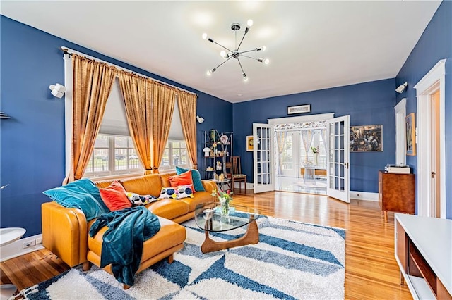 living area featuring french doors, baseboards, a notable chandelier, and wood finished floors
