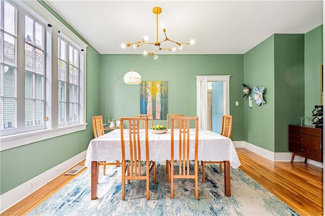 dining room featuring a notable chandelier, baseboards, visible vents, and wood finished floors