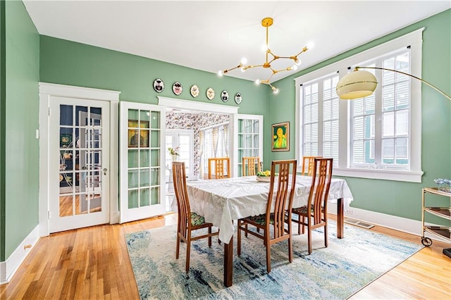 dining space featuring visible vents, baseboards, a notable chandelier, and wood finished floors