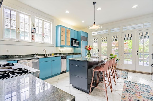 kitchen with a kitchen bar, a center island, blue cabinets, a sink, and stainless steel appliances