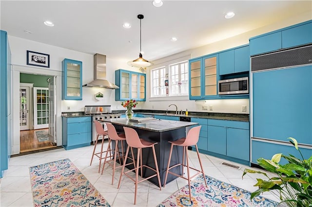 kitchen with built in appliances, a kitchen breakfast bar, wall chimney range hood, light tile patterned floors, and visible vents