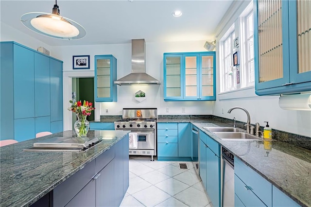 kitchen featuring high end range, light tile patterned floors, wall chimney exhaust hood, glass insert cabinets, and a sink