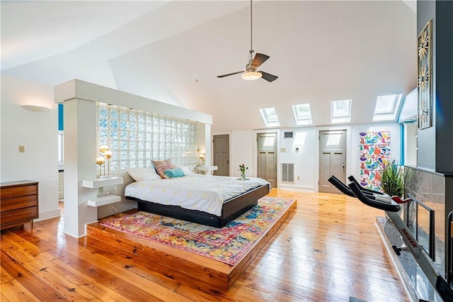 bedroom featuring light wood-style floors, multiple windows, visible vents, and lofted ceiling with skylight
