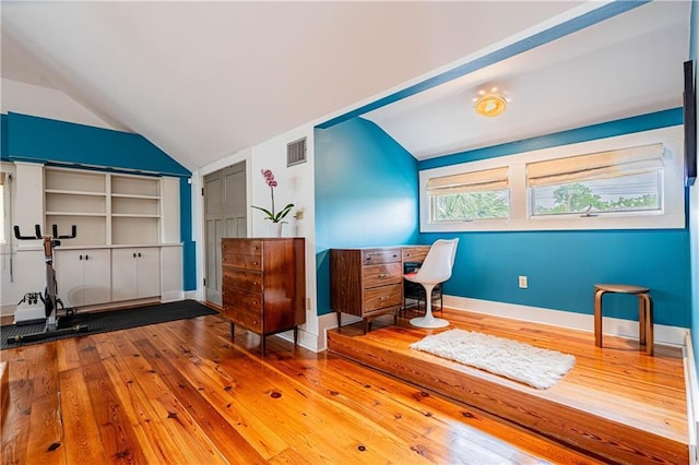 office area featuring baseboards, vaulted ceiling, visible vents, and hardwood / wood-style flooring