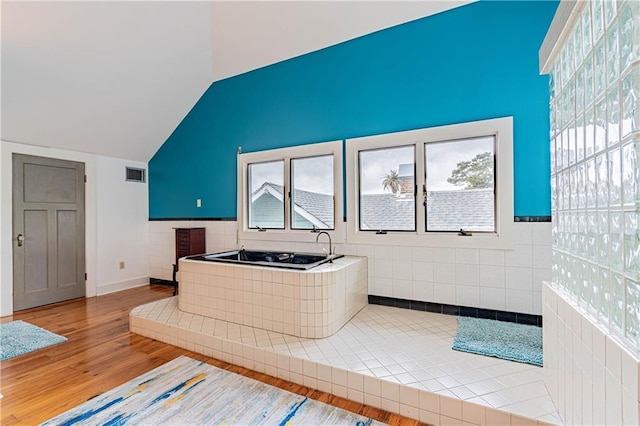 bathroom with visible vents, wood finished floors, and lofted ceiling