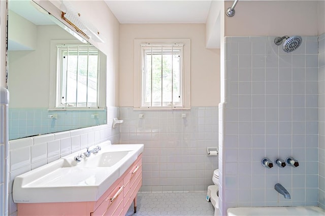 bathroom featuring vanity, tile patterned flooring, wainscoting, tile walls, and shower / bathing tub combination