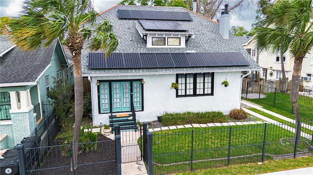 view of front facade with a front yard, a chimney, roof mounted solar panels, and a fenced front yard