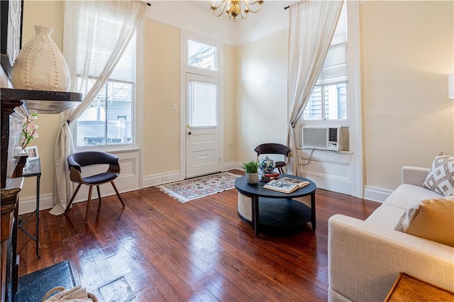 living area with cooling unit, wood finished floors, a notable chandelier, and baseboards