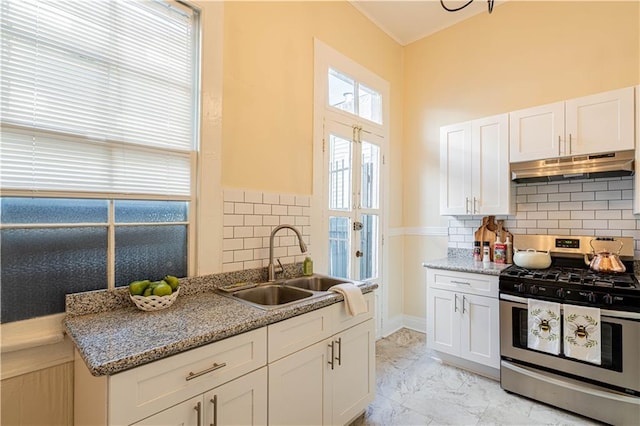 kitchen with white cabinets, a sink, under cabinet range hood, stainless steel gas range oven, and marble finish floor