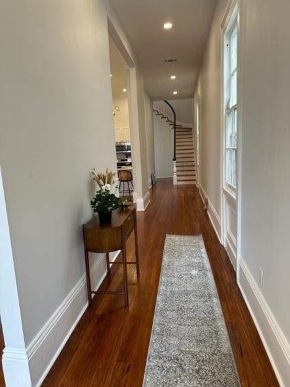 hallway featuring baseboards, stairway, and wood finished floors
