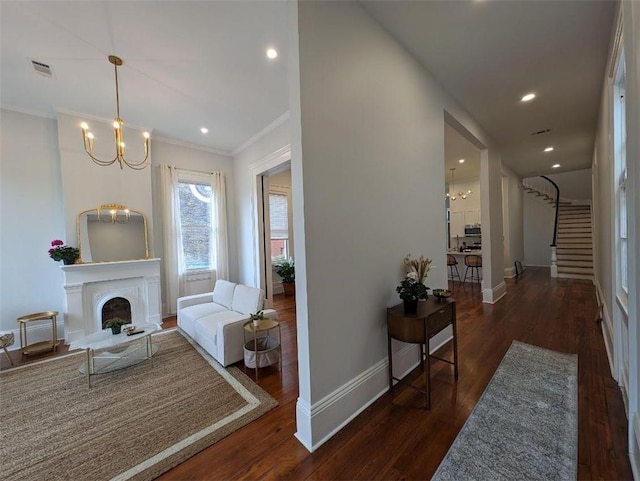 interior space featuring visible vents, baseboards, an inviting chandelier, wood finished floors, and stairs