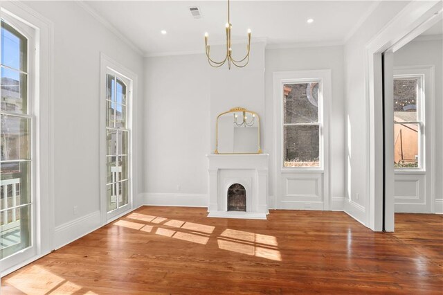 unfurnished living room with a notable chandelier, ornamental molding, and wood finished floors