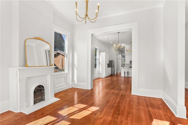interior space featuring a chandelier, baseboards, ornamental molding, and wood finished floors