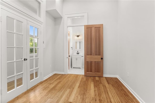 interior space with light wood-style floors, french doors, and baseboards