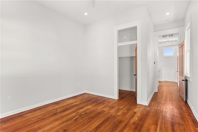 unfurnished bedroom featuring visible vents, baseboards, a closet, a spacious closet, and hardwood / wood-style flooring