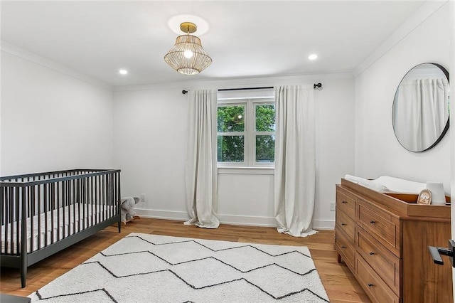102 Liberty St, Belle Chasse, LA 70037 - bedroom featuring crown molding, baseboards, a nursery area, and light wood-style floors