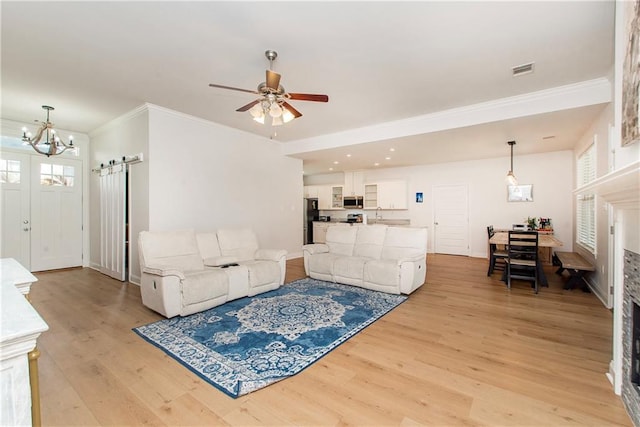 201 Belle Pointe Dr, Madisonville, LA 70447 - living room with a barn door, light wood finished floors, ceiling fan, a chandelier, and ornamental molding