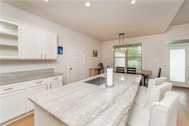 201 Belle Pointe Dr, Madisonville, LA 70447 - kitchen with light wood-style floors, white cabinets, a center island with sink, recessed lighting, and light stone counters