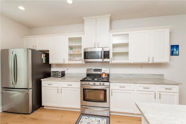201 Belle Pointe Dr, Madisonville, LA 70447 - kitchen with stainless steel appliances, white cabinetry, light wood-style floors, glass insert cabinets, and recessed lighting