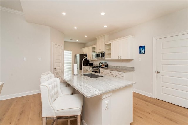 201 Belle Pointe Dr, Madisonville, LA 70447 - kitchen with appliances with stainless steel finishes, a sink, a center island with sink, light wood-type flooring, and white cabinetry