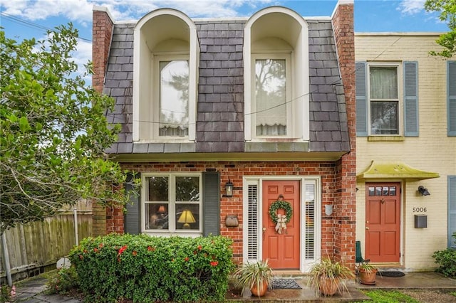 5004-0606 Newlands St, Metairie, LA 70006 - view of front facade featuring mansard roof, fence, and brick siding